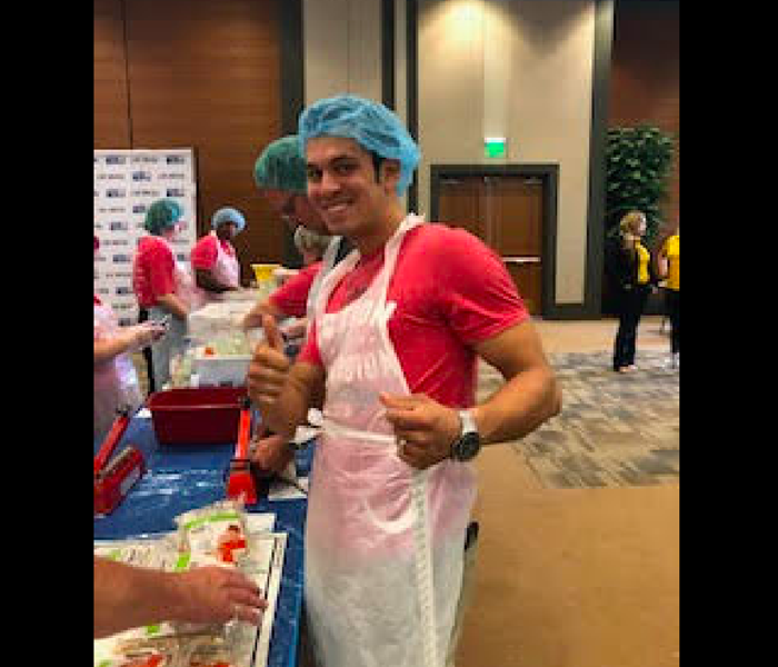 Dressed in a pink shirt and blue hairnet our employee is working hard volunteering. 