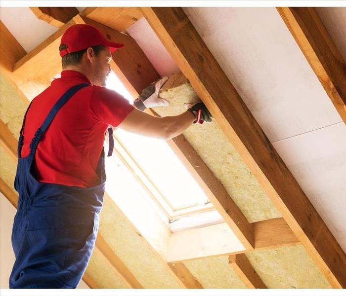 A man adding insulation to attic walls. 